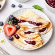 close up shot of sourdough crepes filled with berry sauce.