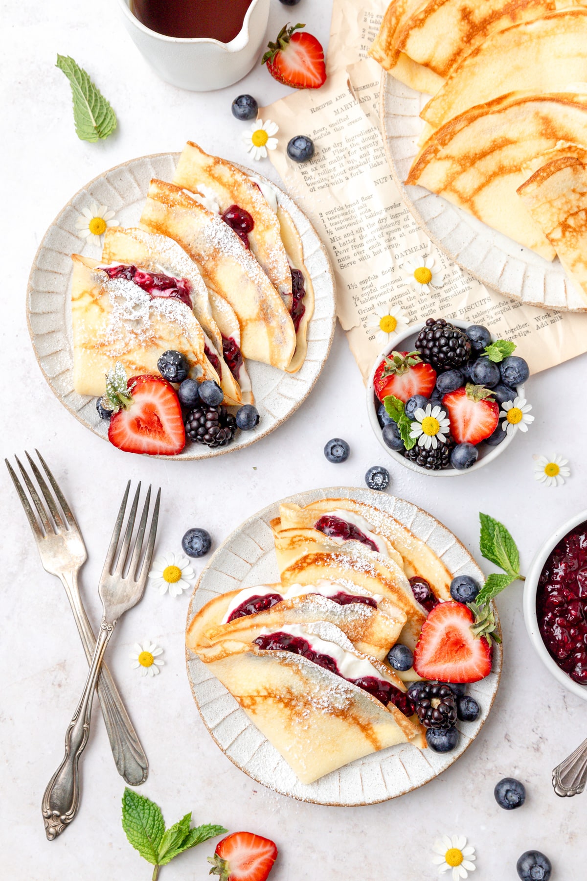 two plates of sourdough crepes filled with whipped cream and fruit.