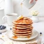 close up shot of stack of sourdough discard pancakes being drizzled with syrup.