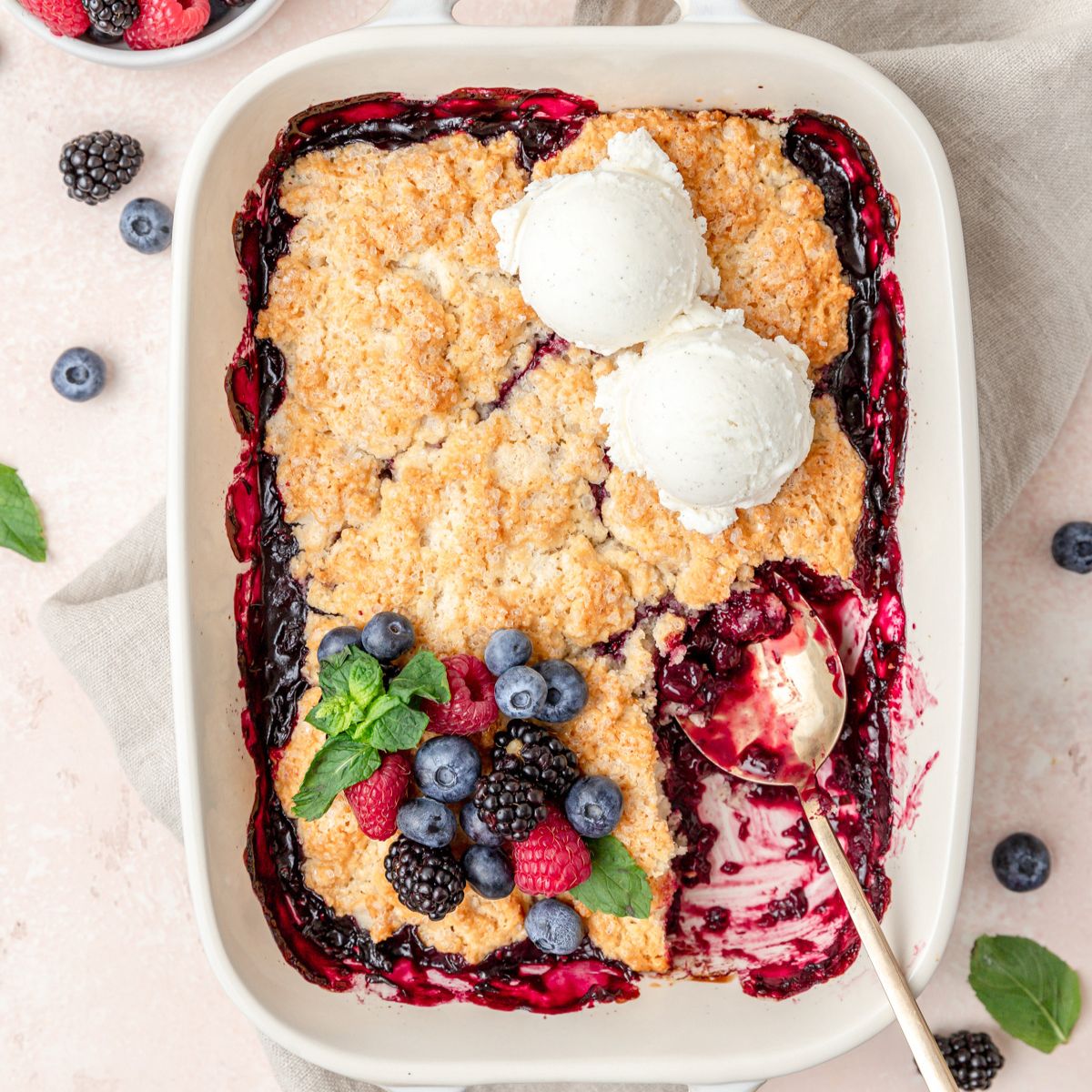 close up shot of mixed berry cobbler topped with vanilla ice cream.