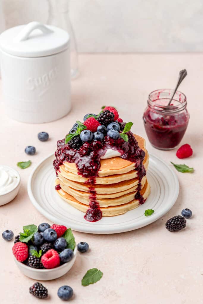 stack of ricotta pancakes with mixed berry sauce.