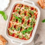 close up of spinach stuffed shells topped with fresh pesto.