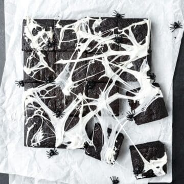 close up of black cocoa brownies with spider web decorations.