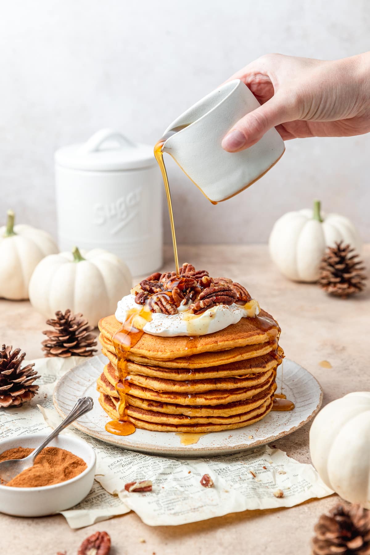 pouring syrup over top of sourdough pumpkin pancakes.