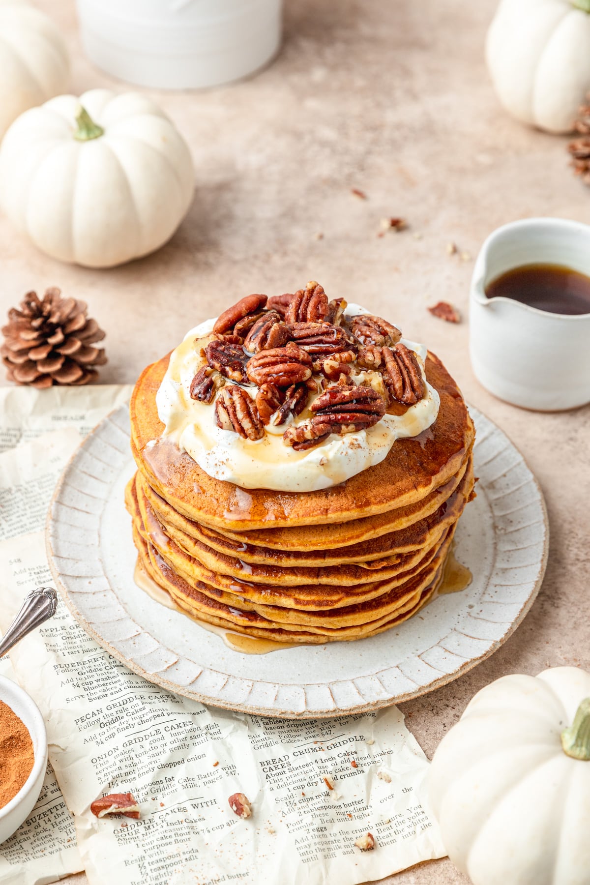 sourdough pumpkin pancakes topped with whipped cream and pecans.