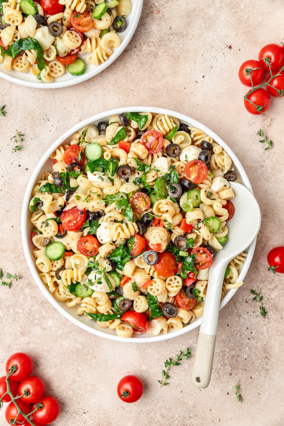 bowl of cold pasta salad with spinach and tomatoes. 