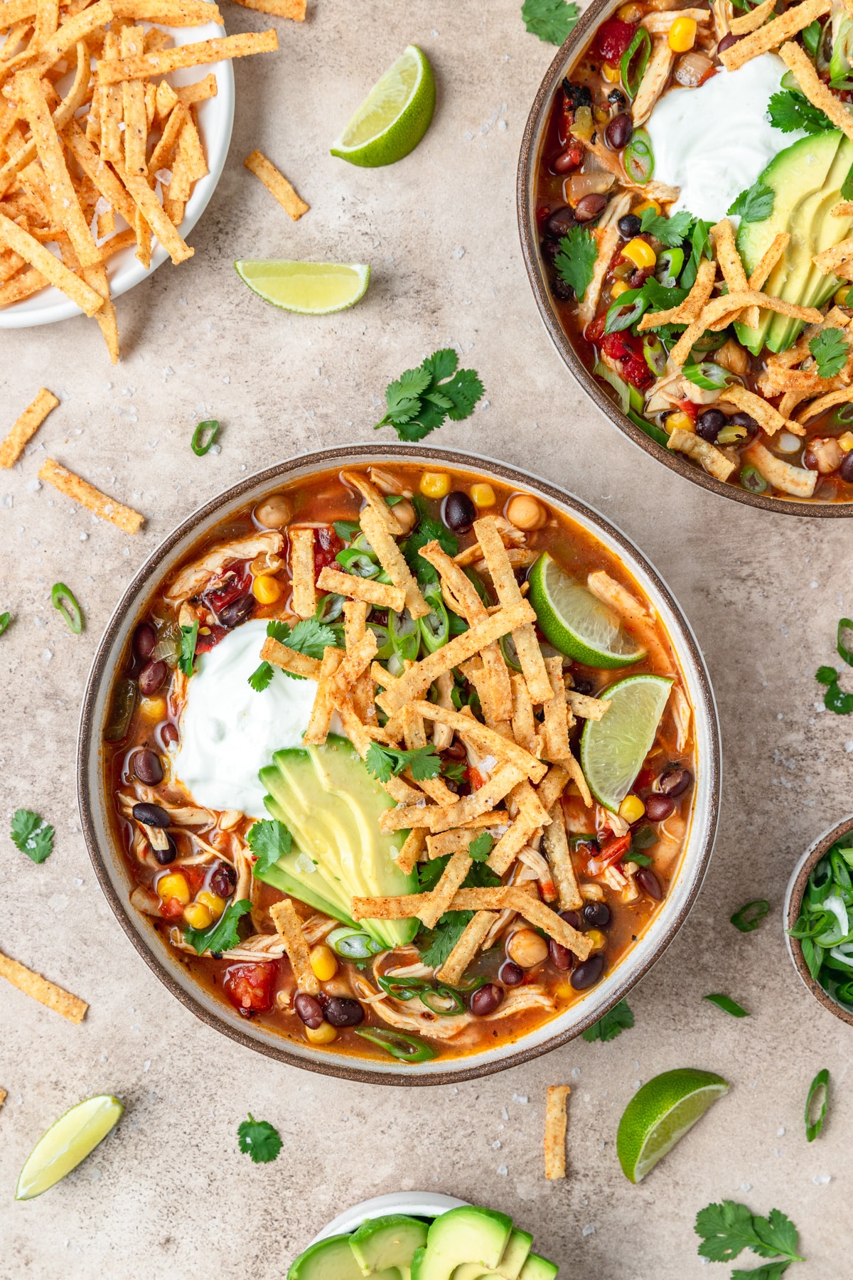 chicken tortilla soup topped with avocado slices and tortilla strips.