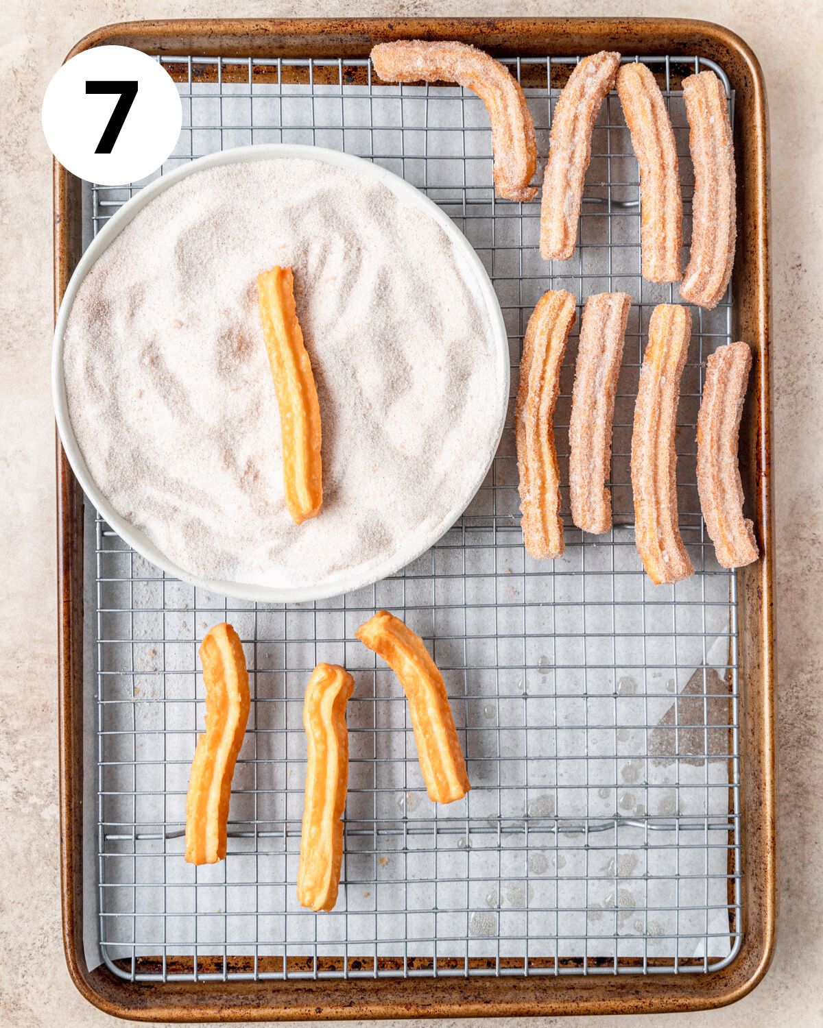 rolling fried churros in cinnamon sugar.