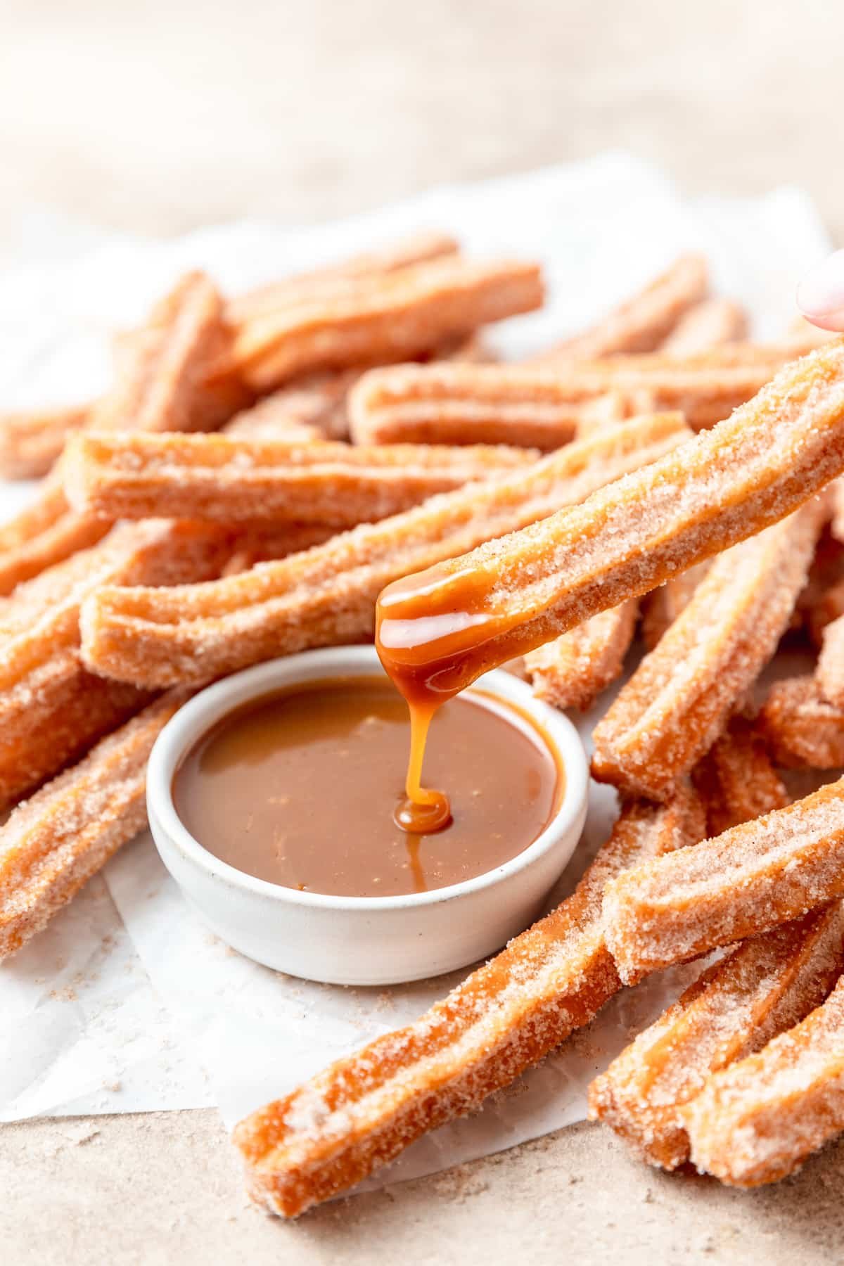 homemade churros being dipped in caramel.