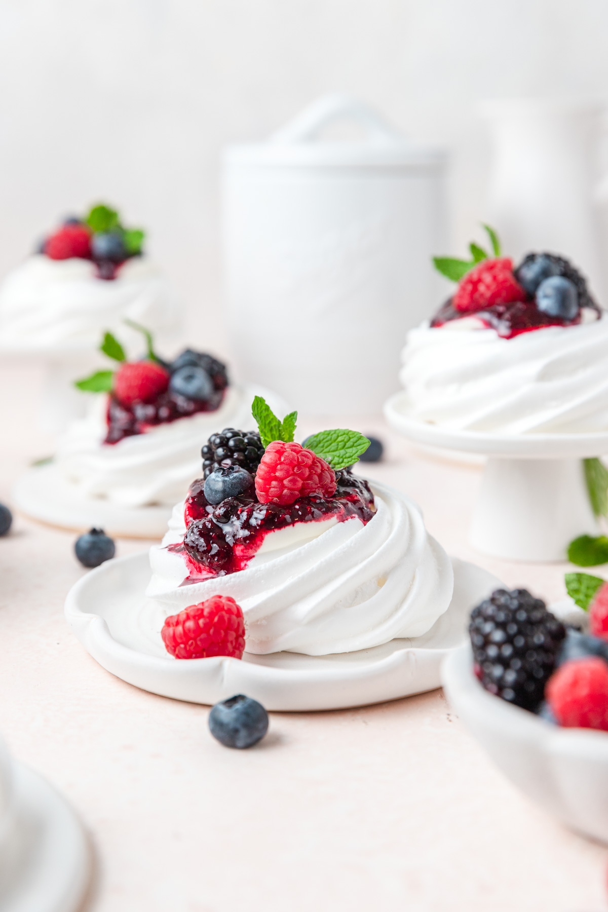 mini pavlovas topped with whipped cream and berries.
