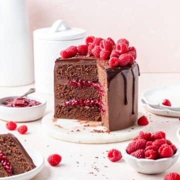 dark chocolate raspberry layer cake with chocolate drip and fresh raspberries.