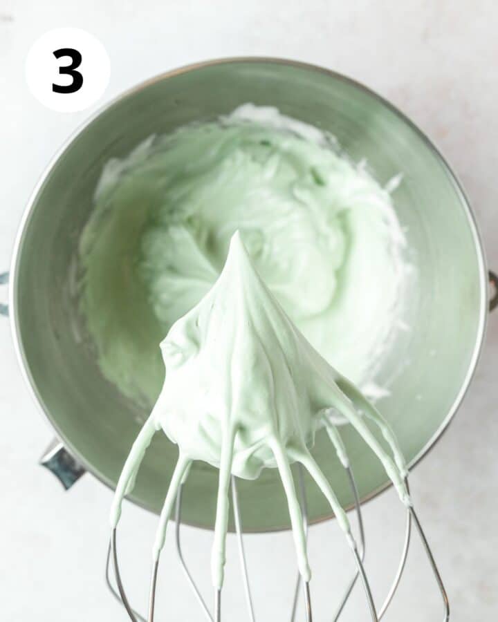 adding in green food coloring and whipping egg whites to stiff peaks.