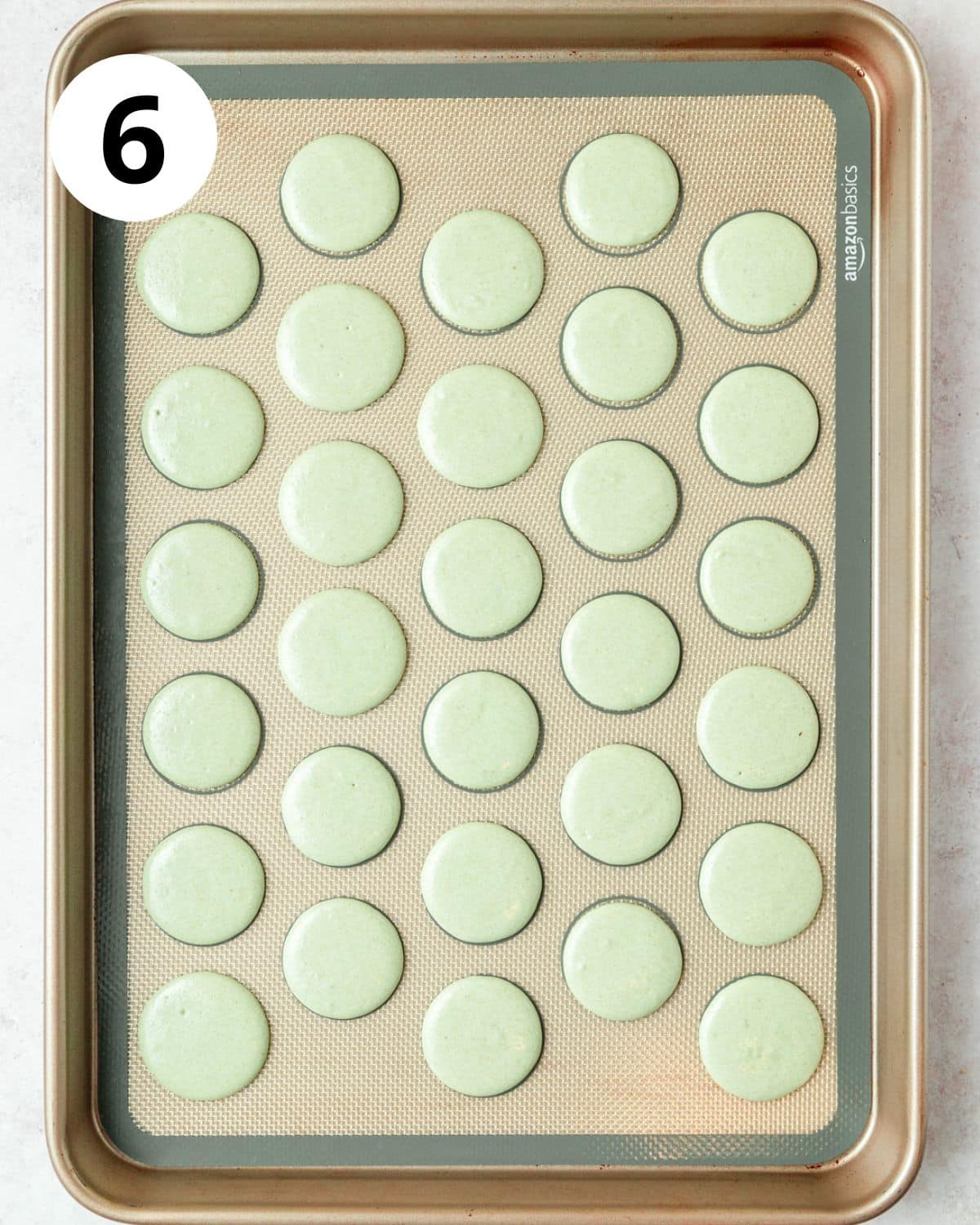 green macarons piped on baking sheet before baking.