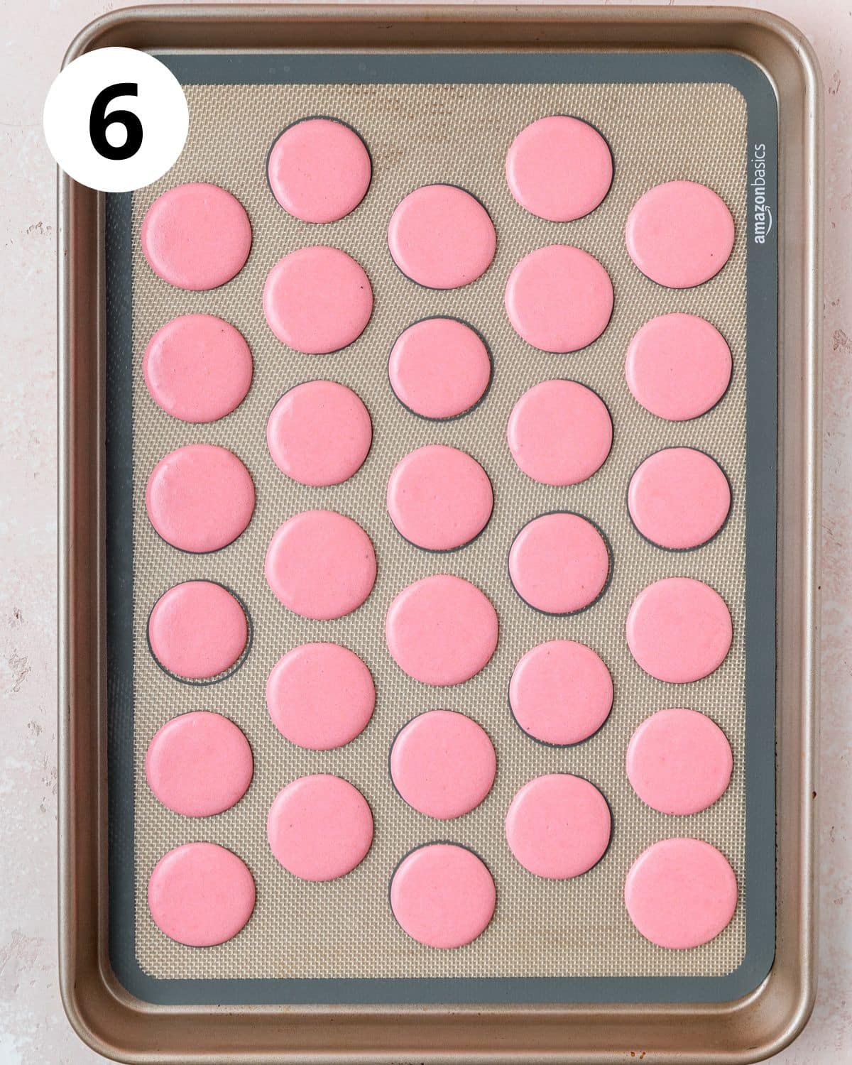 pink macarons piped on baking sheet before baking.