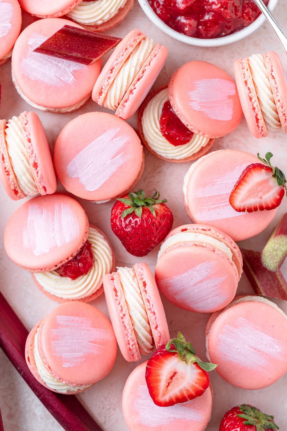 pink strawberry rhubarb macarons painted with white streaks on top.
