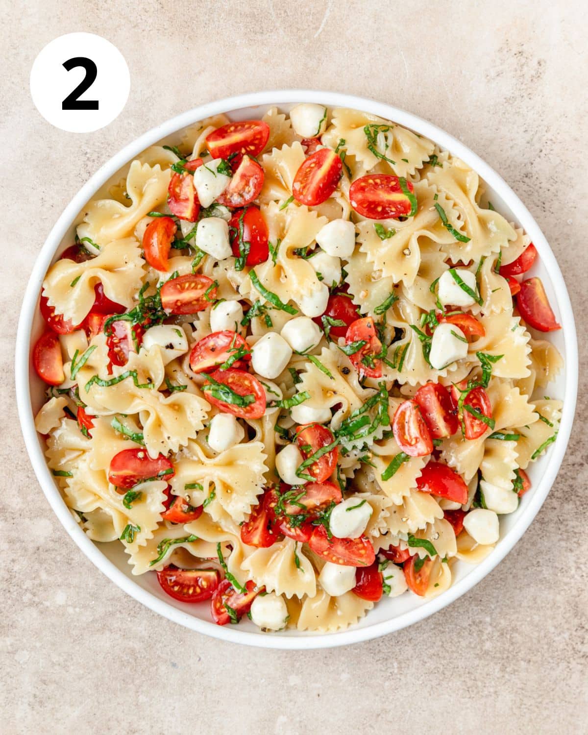 caprese pasta salad tossed together in large bowl.