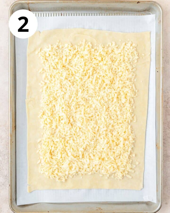 spreading shredded white cheddar cheese over pie dough.