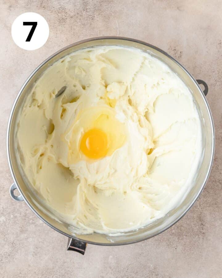 adding eggs to cream cheese one at a time.