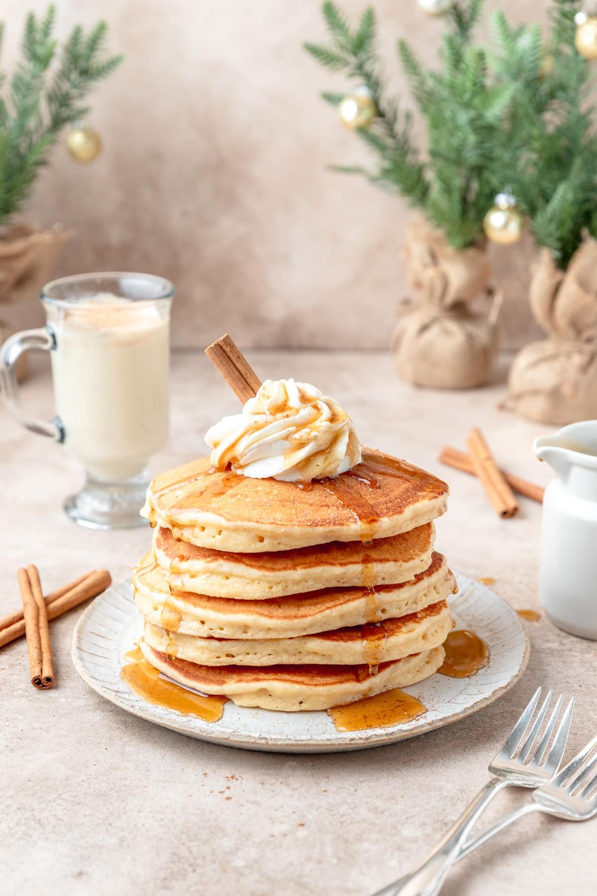 eggnog pancakes topped with whipped cream, maple syrup, and nutmeg.
