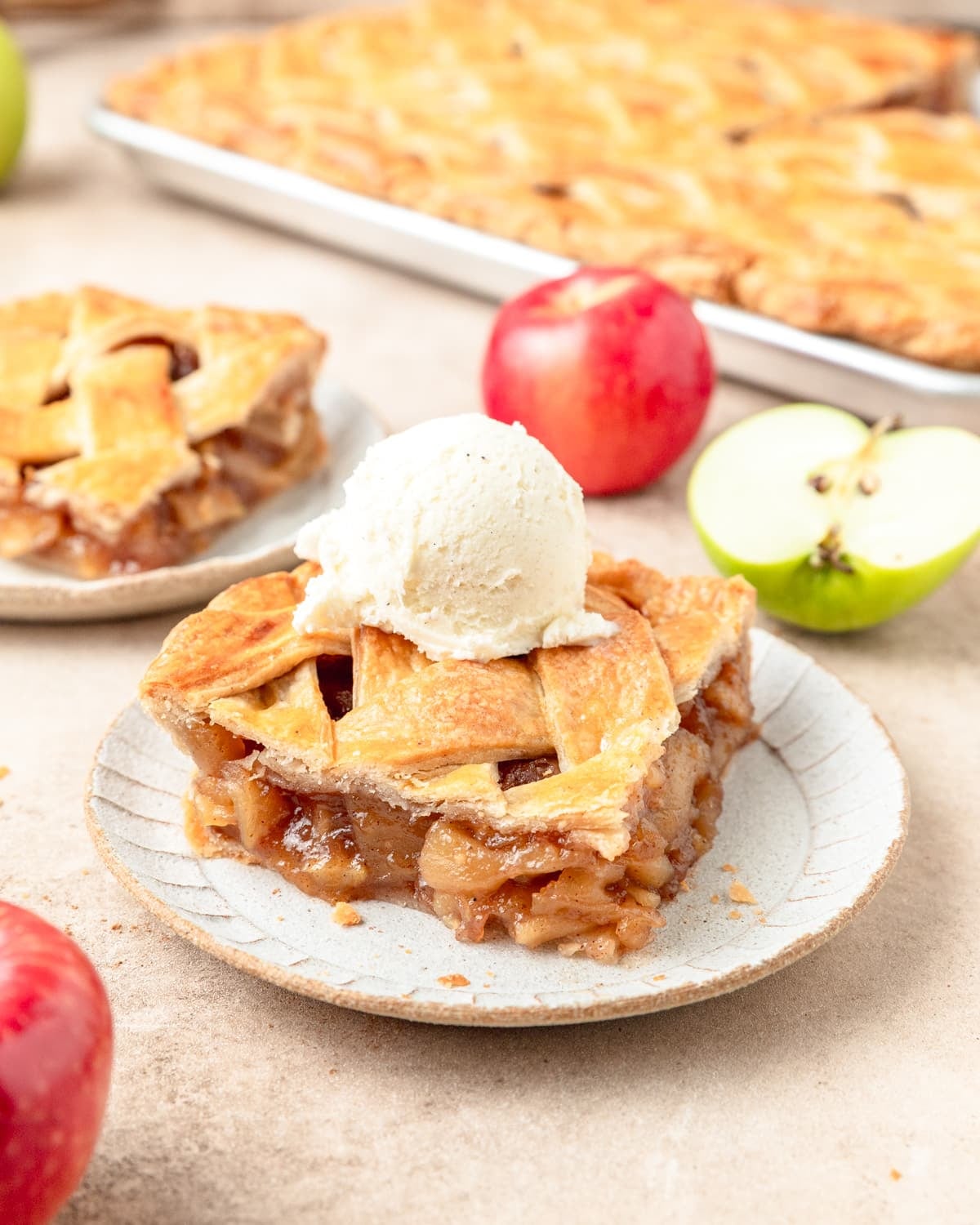 square slice of slab apple pie with ice cream on top.